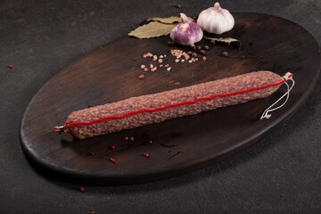 Dry-cured and smoked sausage on a dark background