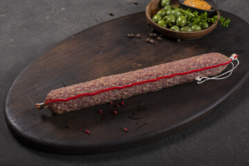 Dry-cured and smoked sausage on a dark background