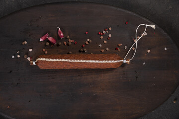 Dry-cured and smoked sausage on a dark background