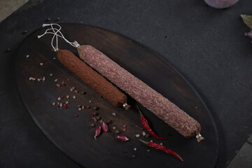 Dry-cured and smoked sausage on a dark background