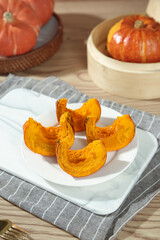 Roasted Pumpkin Slices on White Plate with Fresh Whole Pumpkins Autumn Food