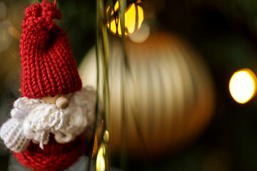 A close-up shot of a handcrafted Christmas gnome ornament hanging on a Christmas tree. The image...
