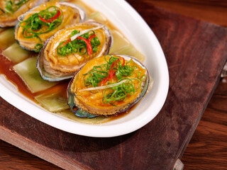 Steamed Abalone with Green Onions and Chili Peppers - Traditional Asian Seafood Dish on White Plate