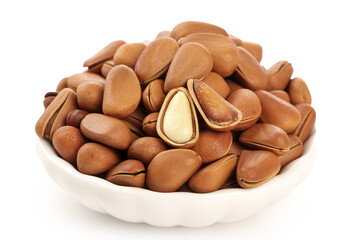 Pine nuts in white bowl with peeled kernels showing - healthy cooking ingredient and nutritious snack