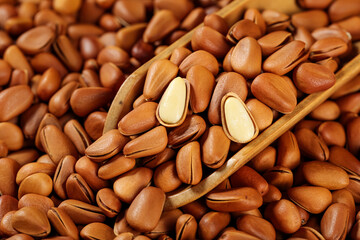Pine nuts in wooden spoon - peeled and unpeeled natural food ingredients