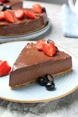 Piece of tasty chocolate cheesecake with berries on light grey textured table, closeup