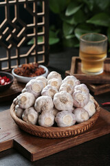 Fresh Shandong Farm Garlic Bulbs in Wicker Basket on Wooden Board with Traditional Asian Kitchen Setting
