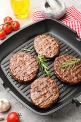 Pan with grilled patties, tomatoes and spices on grey table, closeup