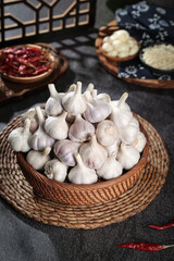 Fresh White Garlic Bulbs in Wicker Basket with Asian Spices on Dark Stone Background