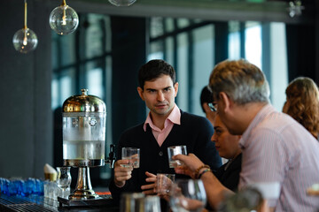Diverse colleagues having casual conversation and drinks in stylish bar, representing international business relationship, networking, and social connection after office hours.