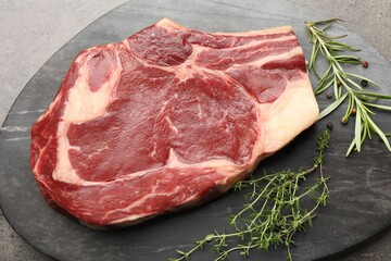 Piece of raw beef meat and spices on grey table, top view