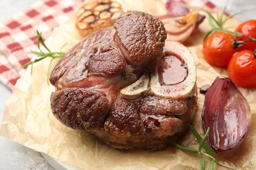 Tasty cut beef steak served with rosemary, garlic and tomatoes on grey textured table, closeup