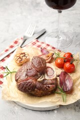 Tasty cut beef steak served with rosemary, garlic, tomatoes and wine on grey textured table, closeup