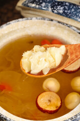 Chinese Lotus Seed Soup with Silver Ear Fungus and Wooden Spoon in Ceramic Bowl