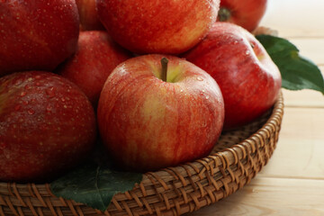 Fresh apples and green leaves on wooden table, closeup