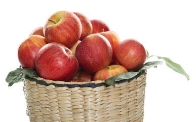 Fresh apples in wicker basket and green leaves isolated on white