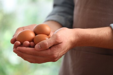 Man with many raw chicken eggs outdoors, closeup