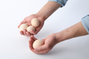 Man with raw chicken eggs on white background, closeup