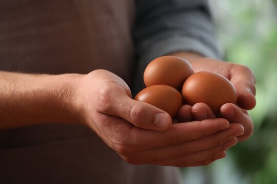 Man with many raw chicken eggs outdoors, closeup