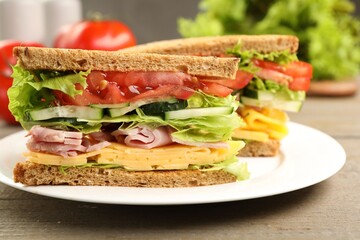 Tasty sandwiches with ham, cheese and vegetables on wooden table, closeup