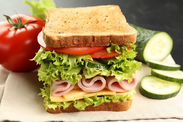 Tasty sandwich with ham, cheese and vegetables on table, closeup