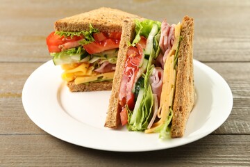 Tasty sandwiches with ham, cheese and vegetables on wooden table, closeup
