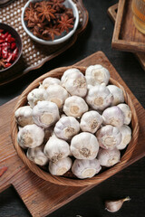Fresh White Garlic Bulbs from Shandong in Wooden Bowl with Spices on Rustic Kitchen Table