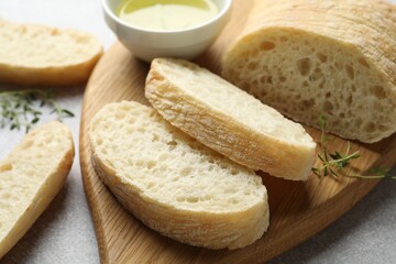 Fresh crispy ciabatta, herbs and oil on grey table, closeup