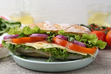 Delicious ciabatta sandwich with prosciutto, cheese and vegetables on light grey table, closeup