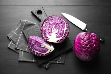 Fresh red cabbages and knife on black wooden table, flat lay