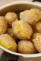 Steamed Gansu Potatoes with Cracked Skin in White Bowl on Wood Surface