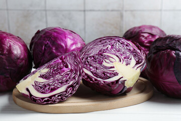 Fototapeta premium Whole and cut fresh red cabbages on white wooden table, closeup