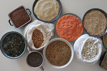 Bowls and bags full of various healthy grains and legumes. Top view.