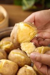 Hand Opening Fresh Steamed Potato Showing Fluffy Yellow Interior