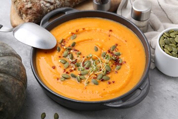 Delicious pumpkin soup served on grey table, closeup