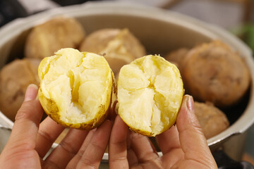 Heart-shaped steamed potatoes with white fluffy interior held in hands closeup