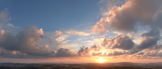 Fototapeta premium Panoramic sunset sky with golden light through clouds over a vast landscape, creating a peaceful and majestic evening scene.