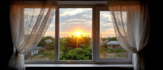 Fototapeta premium Breathtaking sunset view from a window with lace curtains overlooking a tranquil rural landscape