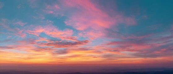 Fototapeta premium Panoramic sunset sky with warm golden, orange, and pink tones blending into soft blue across a wide horizon.
