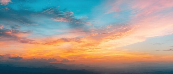 Obraz premium Panoramic sunset sky with warm golden, orange, and pink tones blending into soft blue across a wide horizon.
