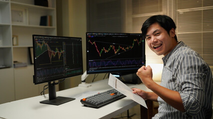 business man congratulations stock trader sitting at a desk in front of computer monitors