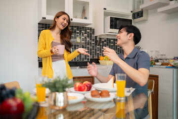 Asian adult couple sharing happy morning breakfast kitchen conversation home lifestyle domestic joy connection bonding cheerful relationship