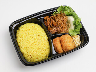 Nasi Kuning or saffron rice served with fried noodle, chicken nuggets, cucumber and lettuce