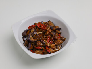 Stir fried eggplants with chili, garlic and onion on white bowl