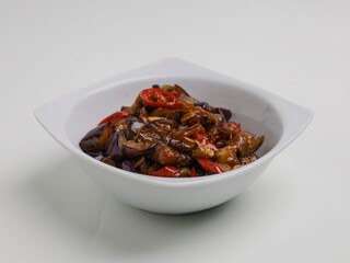 Stir fried eggplants with chili, garlic and onion on white bowl