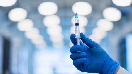 A close-up shot features a blue-gloved hand carefully holding a medical syringe
