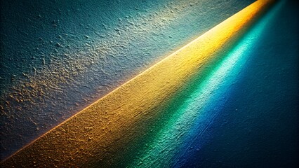 A diagonal beam of golden and turquoise light cuts across a textured, dark blue surface, creating a striking contrast and abstract visual effect