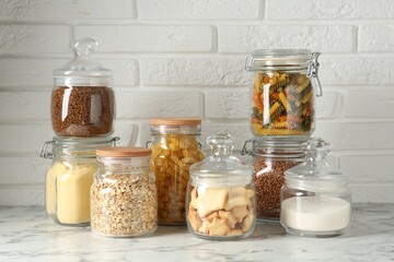 Glass jars with different products on white marble table