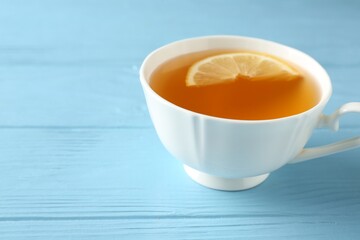 Aromatic tea with lemon in cup on light blue wooden table, closeup. Space for text