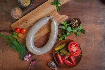 Meat delicacies on a wooden table in the kitchen among greens and vegetables